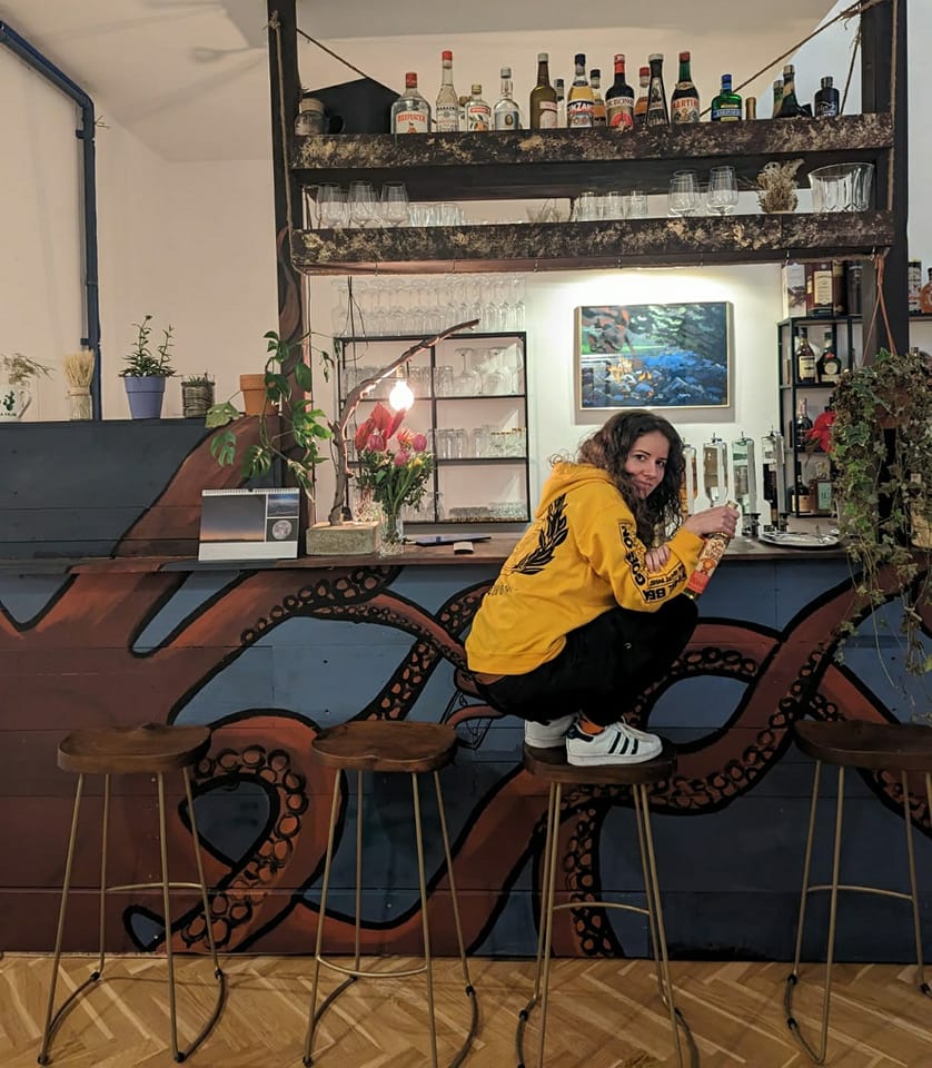 lucy squatting in front of the bar "Galeria"